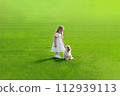 A young girl looks at a puppy in a park with green grass. pet, love image 112939113