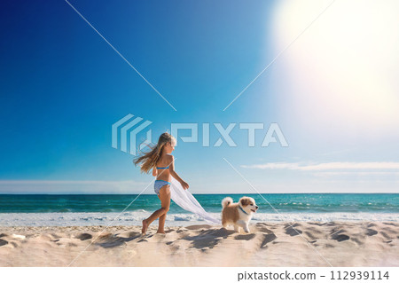 Little girl playing with a puppy on the beach at the seashore with blue sky background Little girl playing with a puppy on the beach at the seashore with blue sky background 112939114