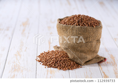 Raw buckwheat in sack on a light table, selective focus. 112939733