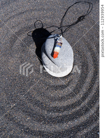 Healing crystals pendulum on black sand background 112939954