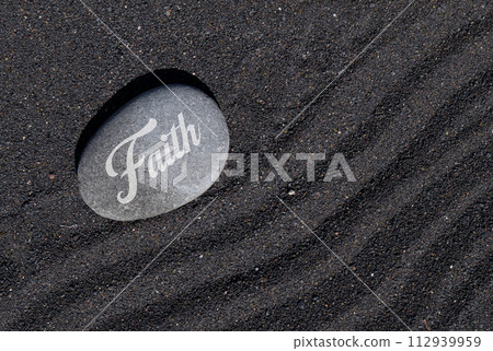 Faith stone on black sand Faith stone on black sand 112939959