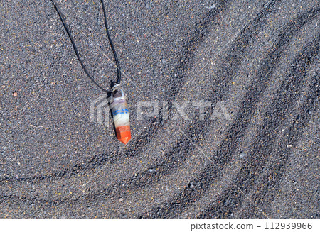 Healing crystals pendulum on black sand background 112939966