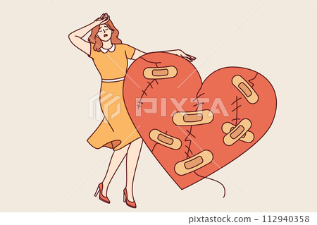Woman cries after breaking up and having problematic relationship, standing near large wounded heart 112940358