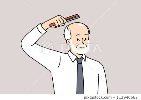 Elderly sad balding man holds comb over head, upset about his loss due to old age 112940662