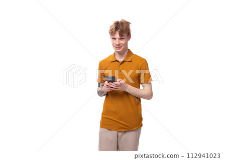 young slender handsome student man with short red hair dressed in a yellow t-shirt chatting on the young slender handsome student man with short red hair dressed in a yellow t-shirt chatting on the 112941023