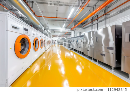 Numerous washing machines lined up in a spacious room, ready for use. The industrial appliances for laundry purposes 112942845