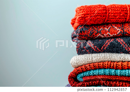 Pile of knitted sweaters and cozy scarves on solid background with copy space, Stack of clothes 112942857
