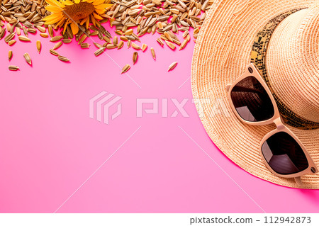 Sunflower seeds, hat and sunglasses on pink background. Top view and summer vibe, border frame with copy space Sunflower seeds, hat and sunglasses on pink background. Top view and summer vibe, border frame with copy space 112942873