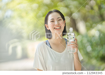 Young woman in sportswear drinking water from a plastic bottle Young woman in sportswear drinking water from a plastic bottle 112943345