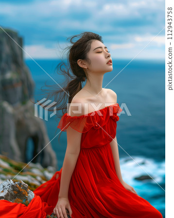 Female model in red dress shooting on a cliff near the sea 112943758