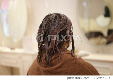 Applying medicine to hair in a beauty salon 112944203