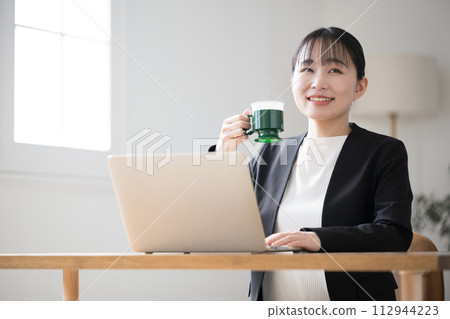 一位女士在工作時喝咖啡，看著窗外 112944223