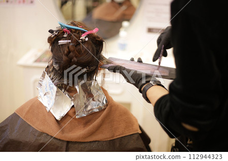 Male hairdresser applying drug to woman's hair 112944323