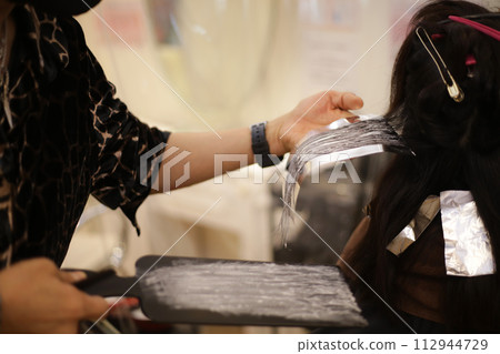 Male hairdresser applying drug to woman's hair Male hairdresser applying drug to woman's hair 112944729