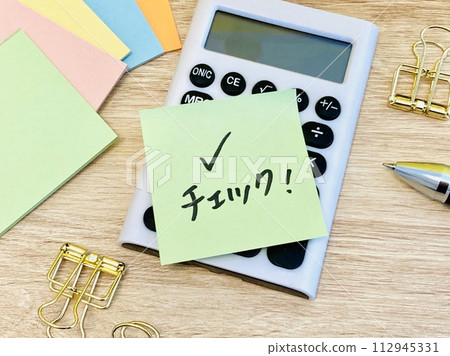 A sticky note with a calculator and a check written on it A sticky note with a calculator and a check written on it 112945331