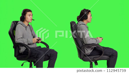 Gamer having fun with rpg challenge over greenscreen background, playing videogames with controller. Young asian guy enjoying online gaming, video game player with coordination skill. 112945739