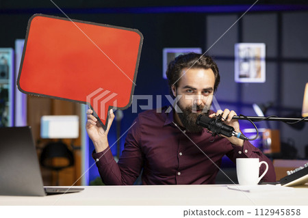 Influencer filming content, holding empty copy space sign, talking in professional microphone. Online star using cardboard bubble speech cutout to do influencer marketing, speaking in high tech mic Influencer filming content, holding empty copy space sign, talking in professional microphone. Online star using cardboard bubble speech cutout to do influencer marketing, speaking in high tech mic 112945858