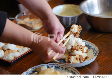 A woman mixing ingredients with freshly pounded mochi A woman mixing ingredients with freshly pounded mochi 112946658