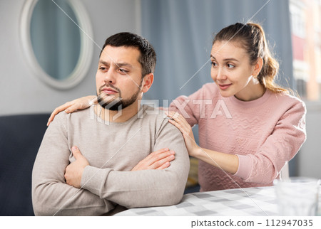 Woman comforting offended husband after spat at home Woman comforting offended husband after spat at home 112947035