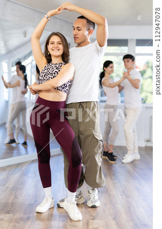 Girl paired up with young man, they train to perform disco fox dance, rehearse performance. 112947078