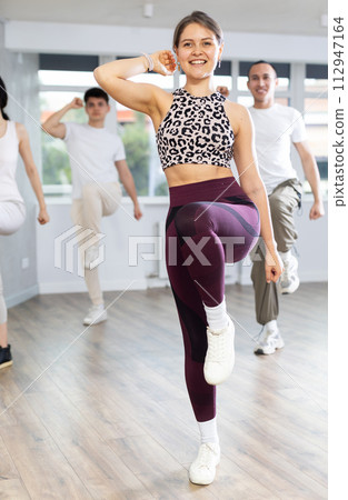 Smiling girl enjoying vigorous dance at group class Smiling girl enjoying vigorous dance at group class 112947164