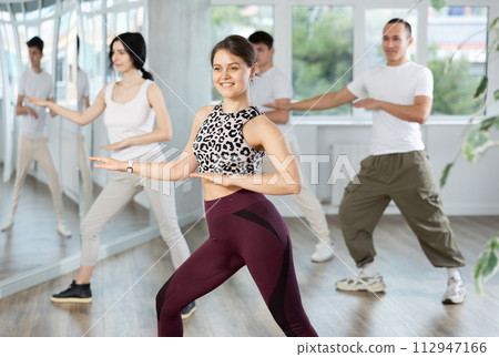 Smiling young people practicing vigorous lindy hop movements in dance class 112947166