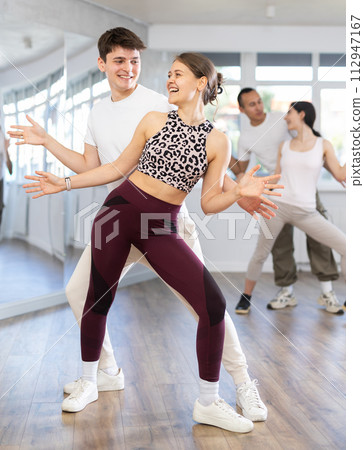 Girl paired up with young man, they train to perform hustle dance, rehearse performance. 112947167