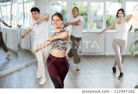 Girl enjoys active dancing, learns new movements, moves synchronously with participants of lesson 112947168