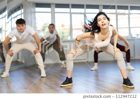 Young girl with waving hair energizing group during dance class Young girl with waving hair energizing group during dance class 112947212