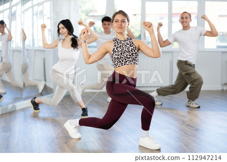Young girl and group of positive people practicing energetic lindy hop movements at dance school Young girl and group of positive people practicing energetic lindy hop movements at dance school 112947214