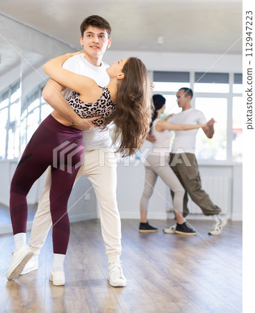 Girl paired up with young man, they train to perform disco fox dance, rehearse performance. 112947223