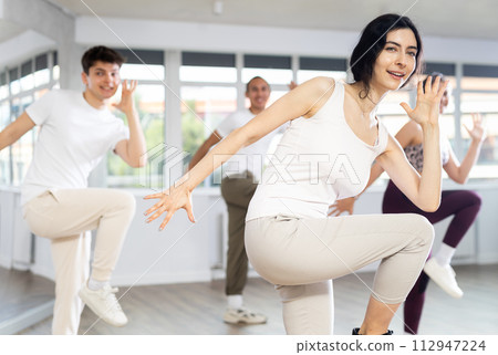 Smiling brunette practicing rhythmic aerobics in fitness studio Smiling brunette practicing rhythmic aerobics in fitness studio 112947224