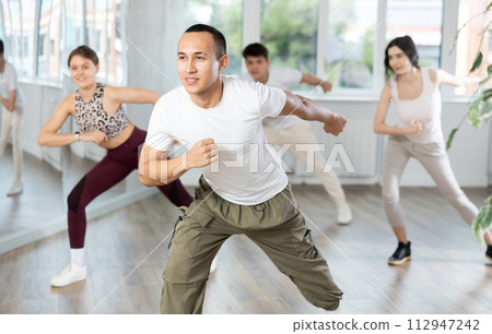 Young Asian man enjoying vigorous dance at group class Young Asian man enjoying vigorous dance at group class 112947242