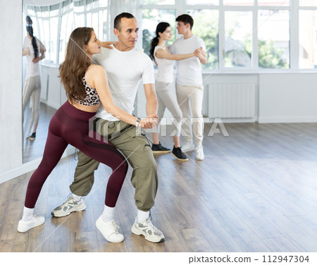 Girl paired up with young man, they train to perform slow waltz dance, rehearse performance. Girl paired up with young man, they train to perform slow waltz dance, rehearse performance. 112947304