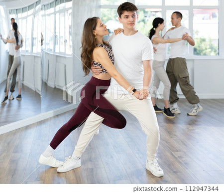 Young couple dancing playful bachata during group class 112947344