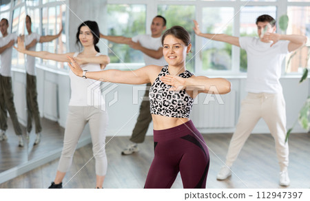 Happy girl and group of multinational young people practicing new modern dance techniques at dance school Happy girl and group of multinational young people practicing new modern dance techniques at dance school 112947397
