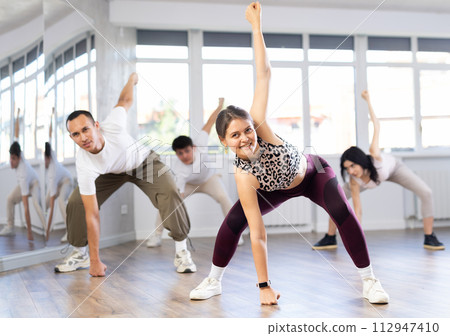 Girl with team of young like-minded people learn to dance modern dances Girl with team of young like-minded people learn to dance modern dances 112947410