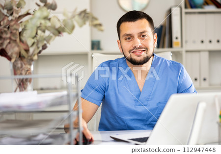Portrait of male doctor using laptop in office 112947448