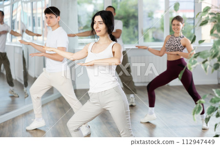 Cheerful brunette practicing energetic dance in choreography class Cheerful brunette practicing energetic dance in choreography class 112947449