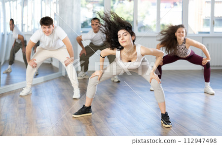 Young girl with waving hair energizing group during dance class Young girl with waving hair energizing group during dance class 112947498