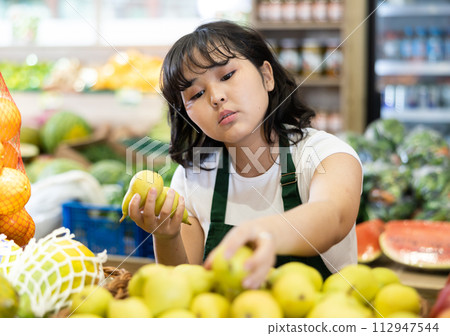 Young asian salesgirl laying out fresh pears on produce display 112947544