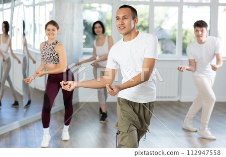 Guy enjoys active dancing, learns new movements, moves synchronously with participants of lesson Guy enjoys active dancing, learns new movements, moves synchronously with participants of lesson 112947558