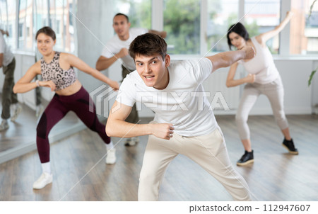 Smiling young people practicing vigorous lindy hop movements in dance class 112947607