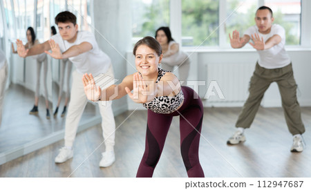 Positive young woman dancing modern dance with other people during group training Positive young woman dancing modern dance with other people during group training 112947687