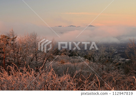 From Karuizawa Old Usui Pass Viewing Platform, the Yatsugatake Mountain Range emerges from the sunrise sky and sea of clouds, covered with frost on the trees. From Karuizawa Old Usui Pass Viewing Platform, the Yatsugatake Mountain Range emerges from the sunrise sky and sea of clouds, covered with frost on the trees. 112947819