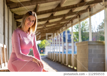 Athletic Rest: Woman in Pink Sportswear Enjoying Urban Solitude 112950533