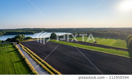Aerial Perspective of Cultivated Fields by a Lake at Sunset 112950594