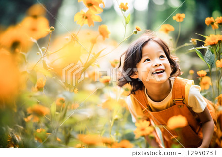 Smiling child playing in a flower garden 112950731