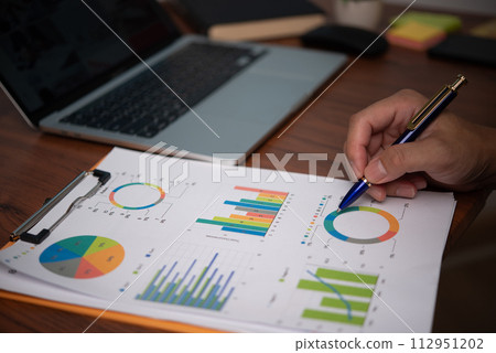 Businessman pointing chart analysis document and paperwork financial plan marketing with laptop on desk office.. Businessman pointing chart analysis document and paperwork financial plan marketing with laptop on desk office.. 112951202