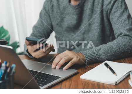 Businessman using mobile phone working and laptop computer digital internet network social media and data communication on desk. Businessman using mobile phone working and laptop computer digital internet network social media and data communication on desk. 112952255